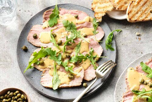 Vitello Tonnato Rezept: Kalbfleischscheiben in einer Thunfischsauce, dekoriert mit Kapern und frischen Kräutern.